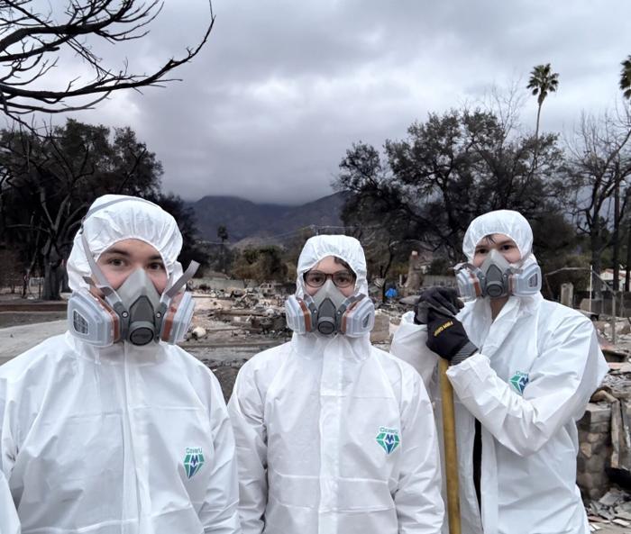 Family members at the burned property in protective equipment